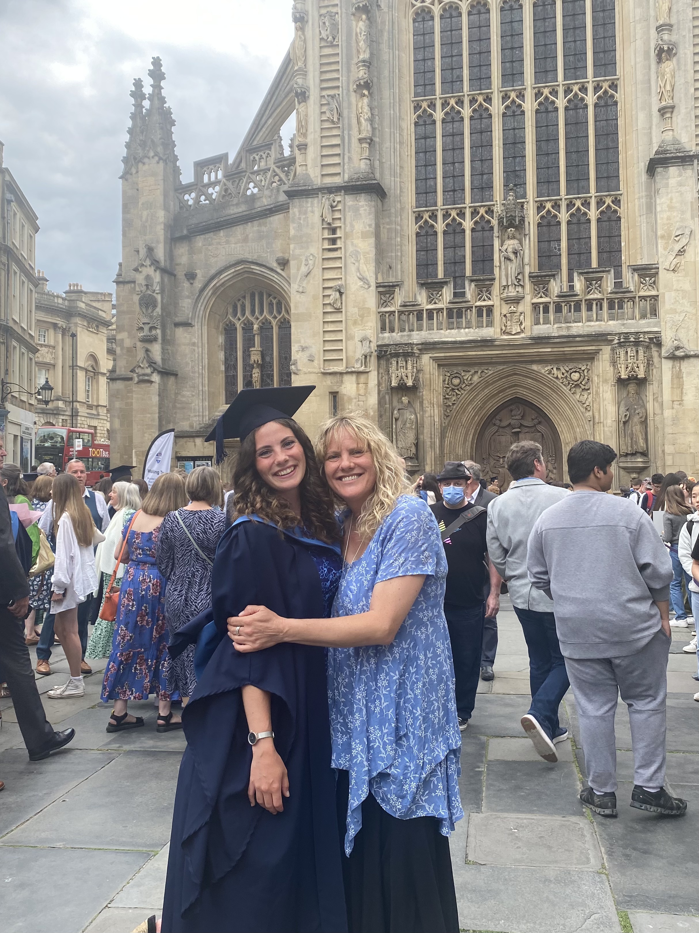 A picture of the author in graduation attire with her mother that has passed away, stood in from of Bath Abbey.