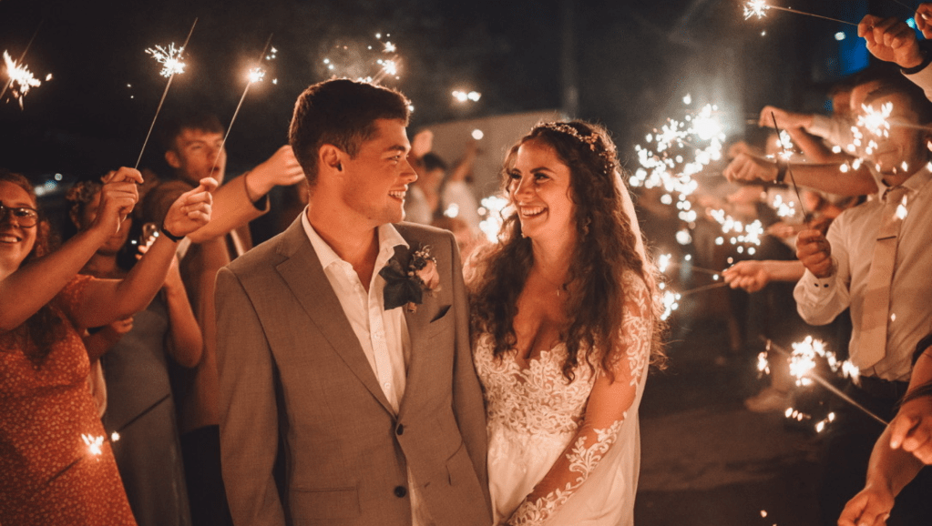 The author is pictured with her husband on their wedding day. There are sparklers and people surrounding them. 